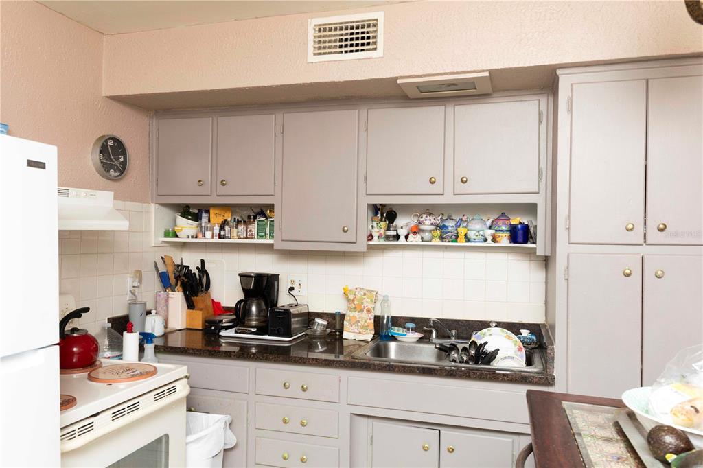 A kitchen features gray cabinets, a dark countertop, a stainless steel sink, and white appliances — 5344 TANGERINE DRIVE, NEW PORT RICHEY, FL