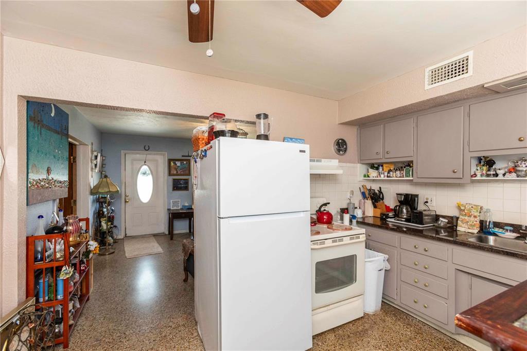 A kitchen features a white refrigerator, gray cabinets, a white stove, and speckled flooring — 5344 TANGERINE DRIVE, NEW PORT RICHEY, FL