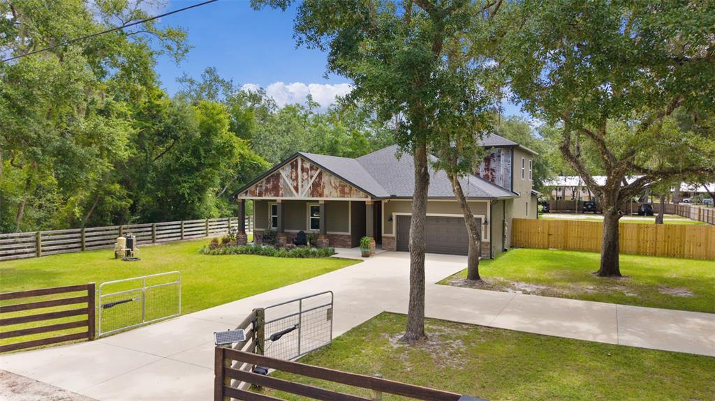 A single-story house with a metal-accented gable, a concrete driveway, and a fenced front yard — 16189 SE 190TH AVENUE, WEIRSDALE, FL