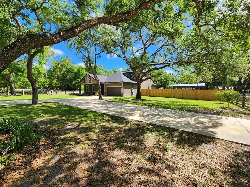 A single-story house with a garage and a long driveway sits on a grassy lot — 16189 SE 190TH AVENUE, WEIRSDALE, FL