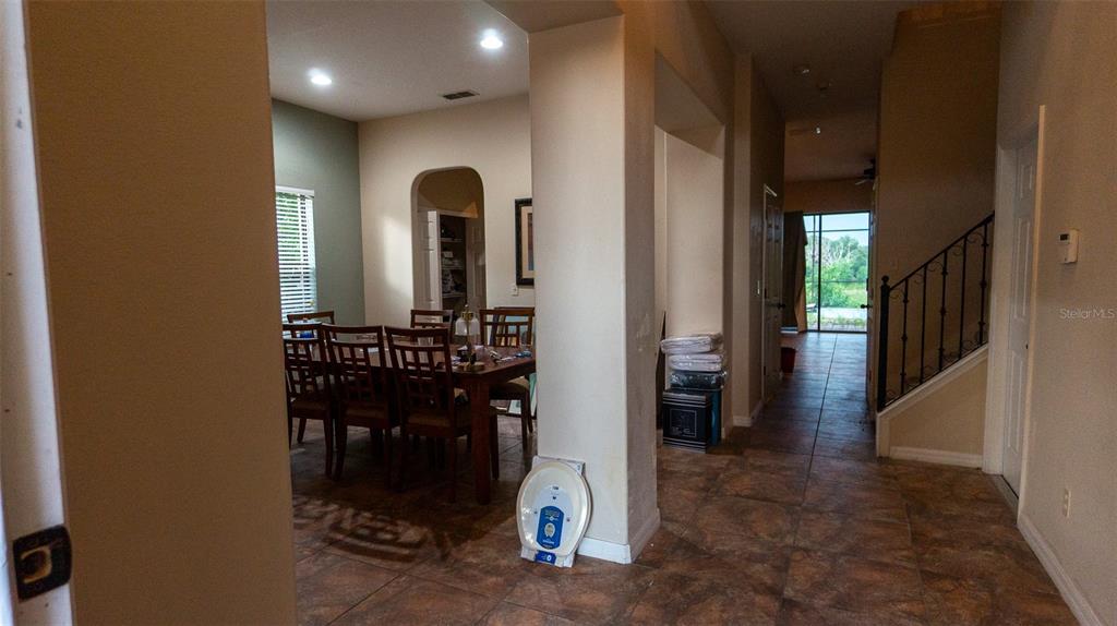 A dining area with a wooden table and chairs sits adjacent to a tiled hallway — 416 BRIDGEFORD CROSSING BOULEVARD, DAVENPORT, FL