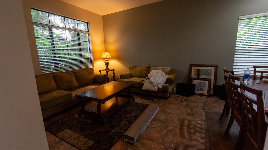 A living room features tile flooring, two sofas, a coffee table, and large windows with blinds — 416 BRIDGEFORD CROSSING BOULEVARD, DAVENPORT, FL