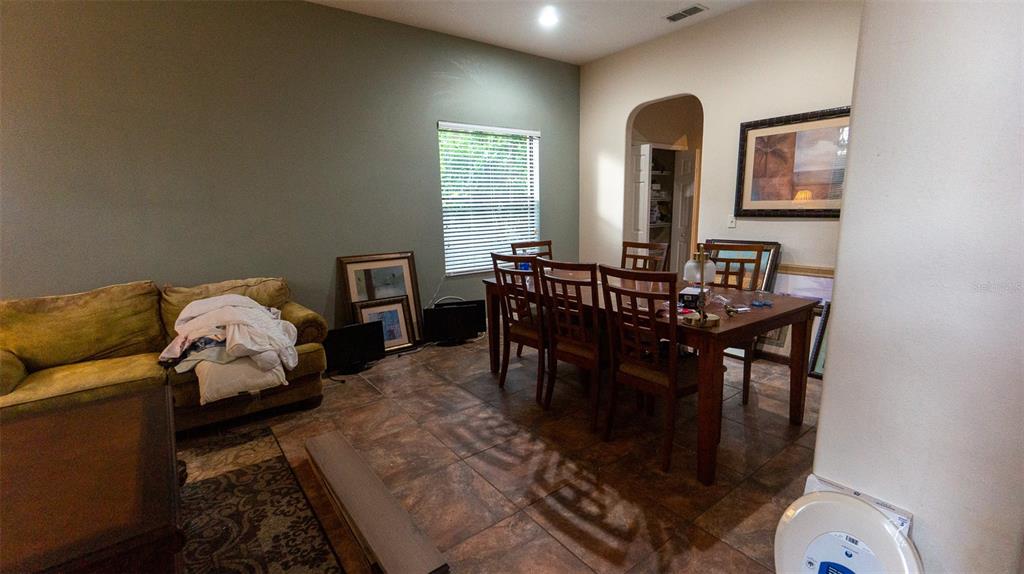 A dining area with a wooden table and chairs sits next to a living room sofa — 416 BRIDGEFORD CROSSING BOULEVARD, DAVENPORT, FL