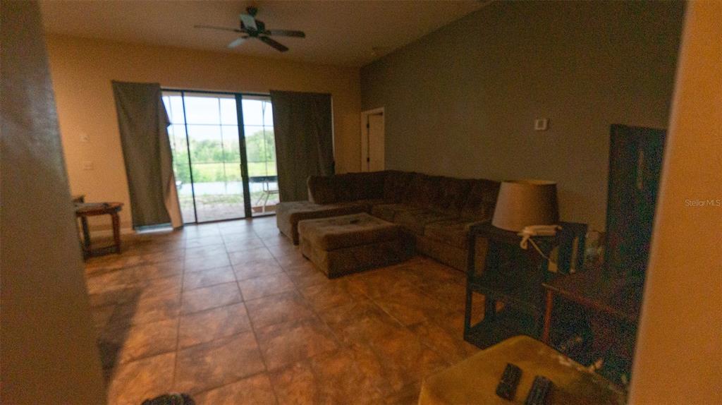 A living room features tile flooring, a large sectional sofa, and sliding glass doors — 416 BRIDGEFORD CROSSING BOULEVARD, DAVENPORT, FL
