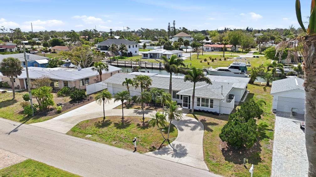An aerial view shows a single-story white house with a circular driveway and canal access — 1959 MISSISSIPPI AVENUE, ENGLEWOOD, FL