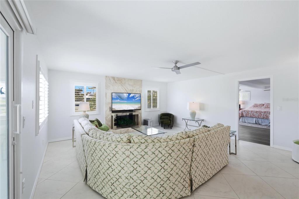 A living room features a large sectional sofa, a fireplace with a television, and tile flooring — 1959 MISSISSIPPI AVENUE, ENGLEWOOD, FL