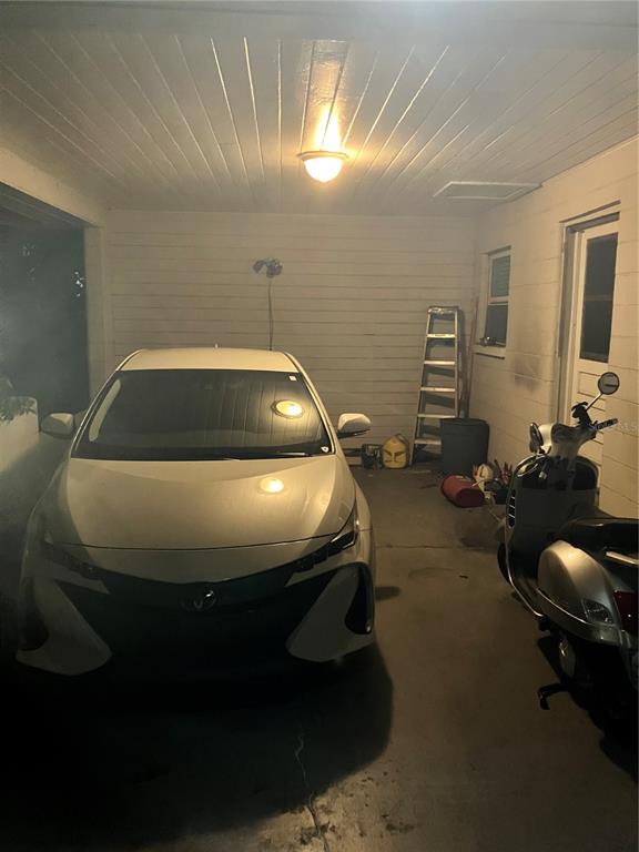 A white car and a scooter are parked in a covered carport with a ladder — 4409 19TH STREET CIRCLE W, BRADENTON, FL