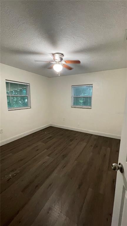 An empty bedroom features white walls, dark wood-look flooring, and a ceiling fan — 4409 19TH STREET CIRCLE W, BRADENTON, FL