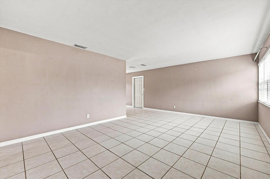 An empty room features light-colored walls, white baseboards, and large square floor tiles — 8380 52ND LANE N, PINELLAS PARK, FL