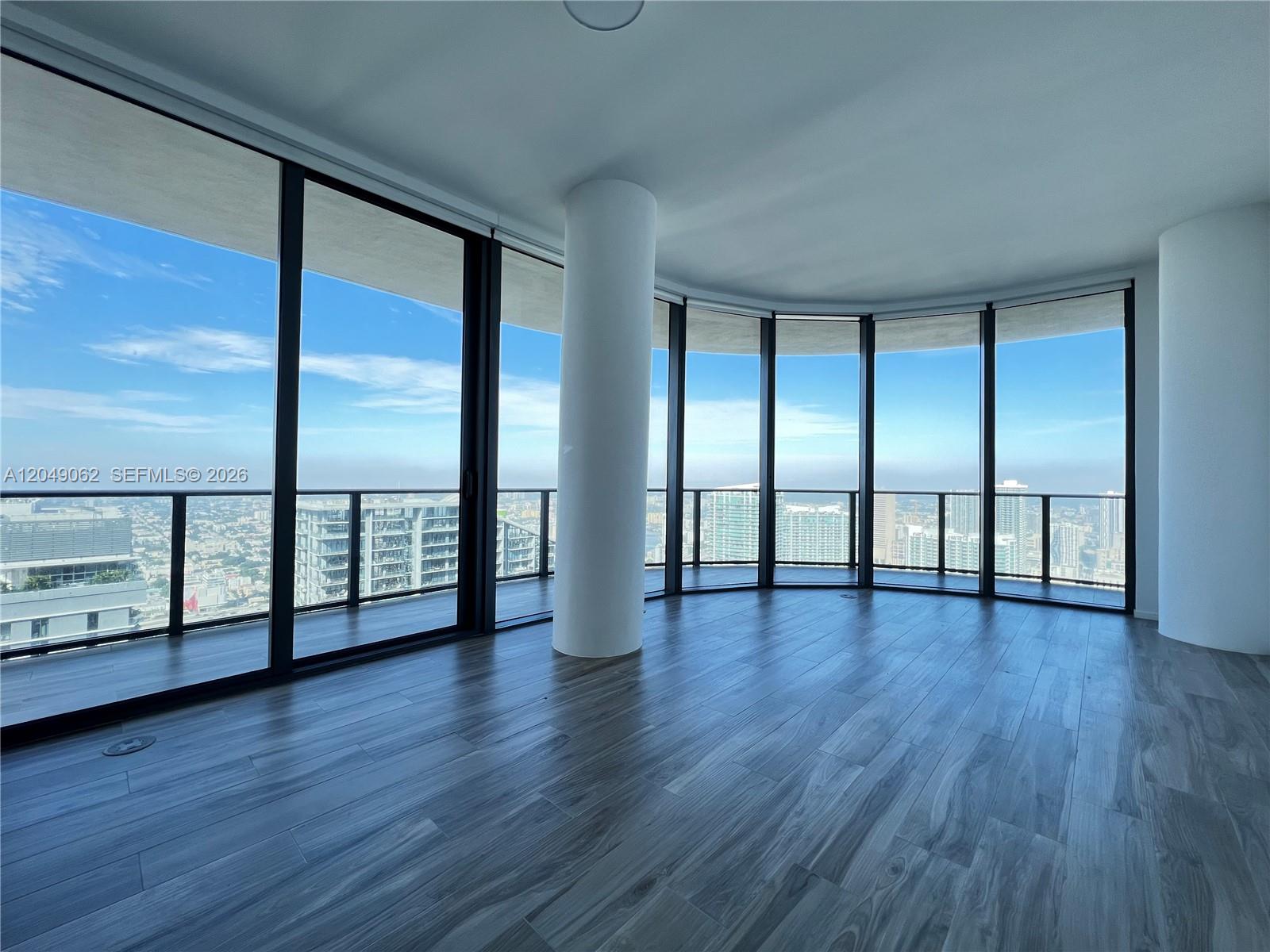 An empty room features floor-to-ceiling windows, wood-look flooring, and a prominent structural column — 801 S Miami Ave # 5309, Miami FL 33130, MIAMI, FL