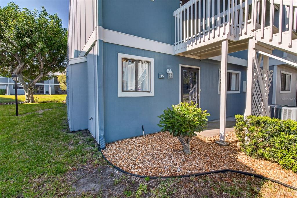 The exterior of a blue two-story residential building features a ground-level entrance and landscaping — 6033 34TH STREET W UNIT 145, BRADENTON, FL