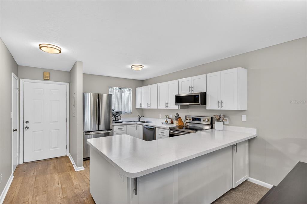 A kitchen features white cabinets, stainless steel appliances, and a peninsula with white countertops — 6033 34TH STREET W UNIT 145, BRADENTON, FL