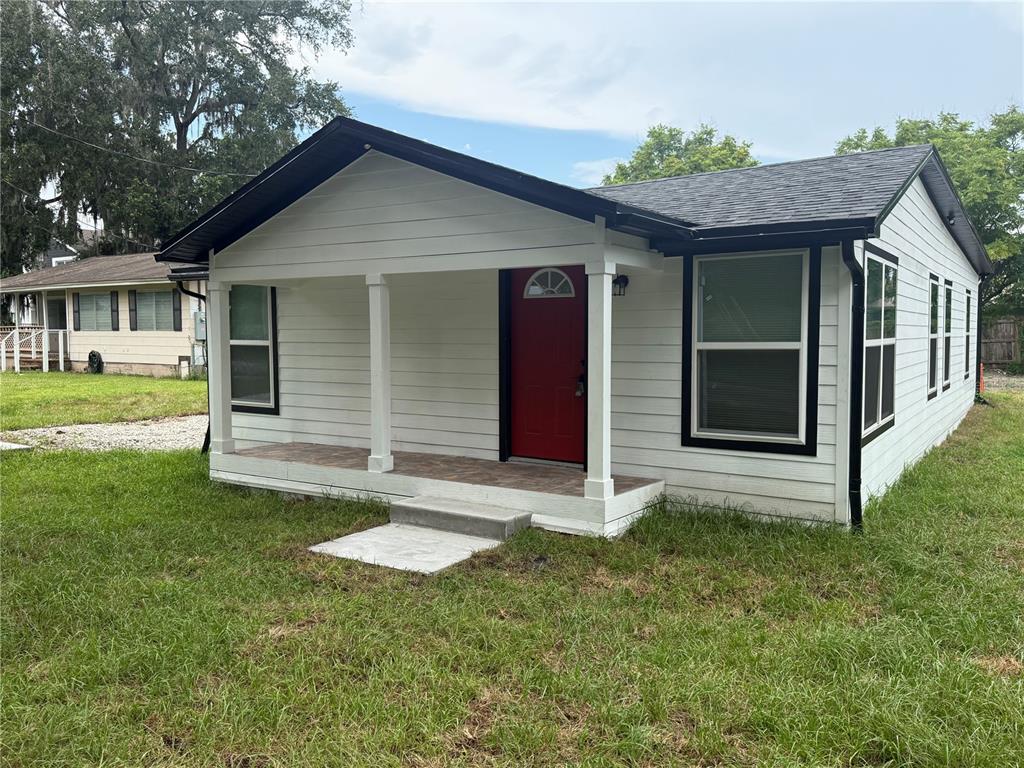 A white house with a red front door, a covered porch, and black trim — 225 E WARREN AVENUE, LONGWOOD, FL