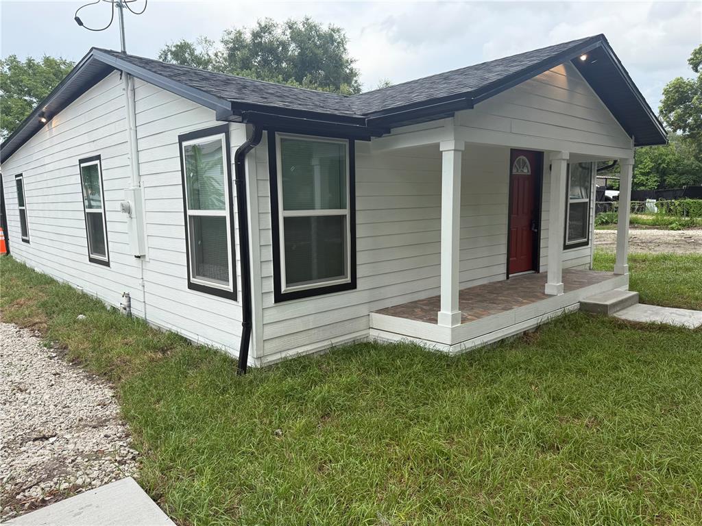 A white house with black trim and a red front door features a covered porch — 225 E WARREN AVENUE, LONGWOOD, FL
