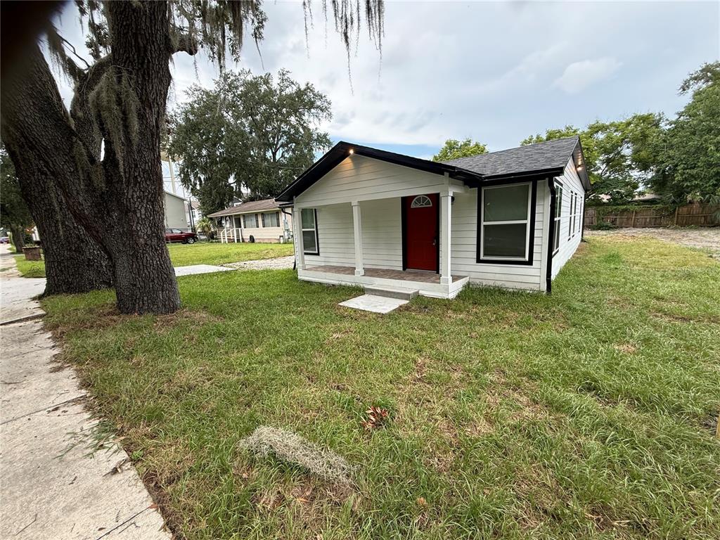 A white single-story house with a red front door and a covered porch — 225 E WARREN AVENUE, LONGWOOD, FL