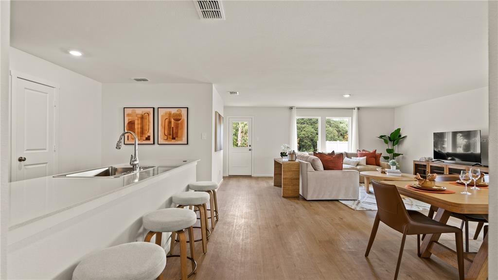 An open-concept living area features a kitchen island with bar stools, dining table, and sofa — 319 CASTLEVIEW DRIVE, DAVENPORT, FL