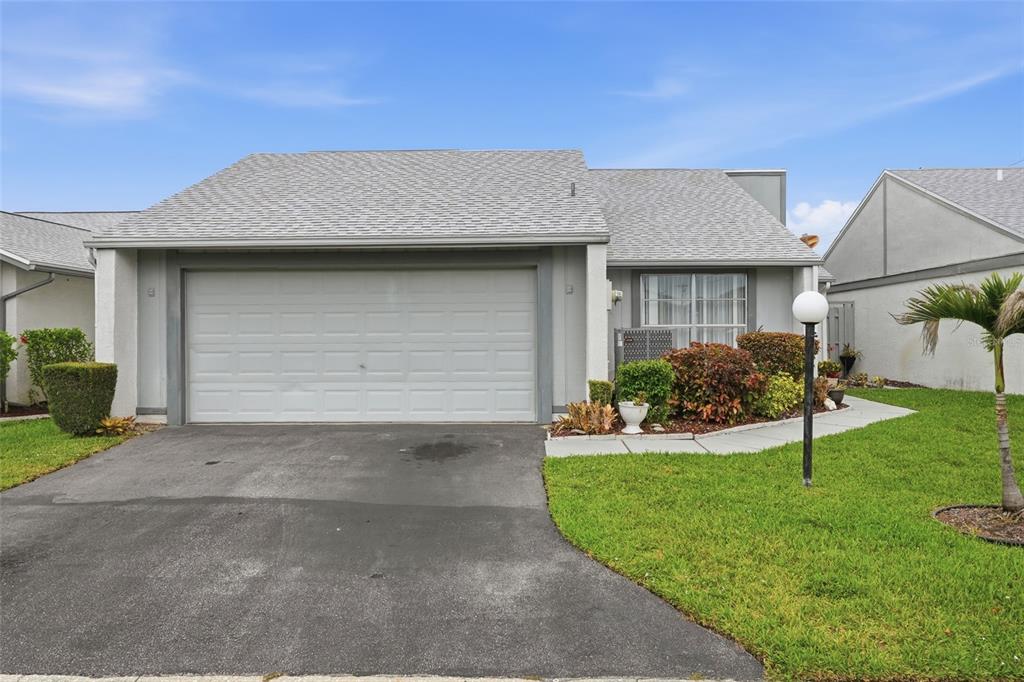 A single-story house with a gray garage door, shingled roof, and a small front lawn — 18441 ORANGECREST COURT, LEHIGH ACRES, FL