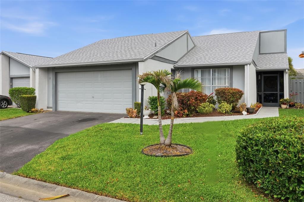 A single-story house with a gray shingled roof, a garage, and a small front lawn — 18441 ORANGECREST COURT, LEHIGH ACRES, FL