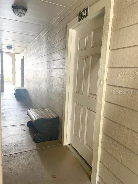 A hallway leads to a white door marked 104 with a bench placed alongside — 3548 TOBAGO LANE UNIT 104, TAMPA, FL