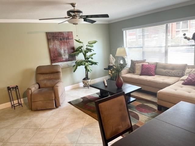 A living room features a beige recliner, a sectional sofa, a coffee table, and tile flooring — 3548 TOBAGO LANE UNIT 104, TAMPA, FL