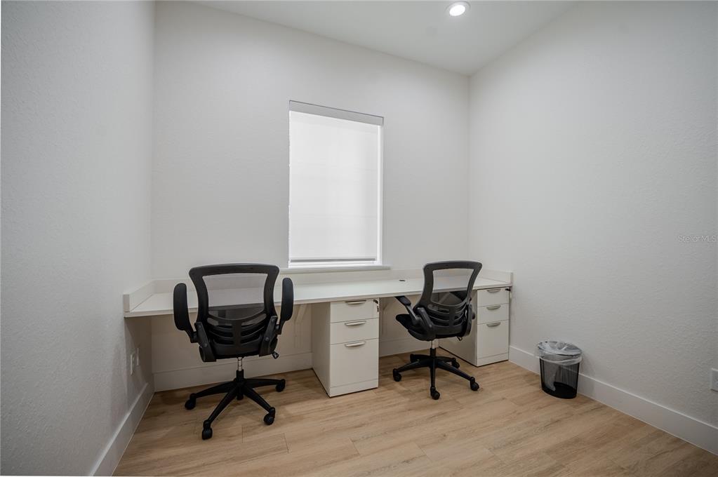 A home office features a long white desk with two chairs and light wood flooring — 6601 SW 80TH AVENUE, OCALA, FL