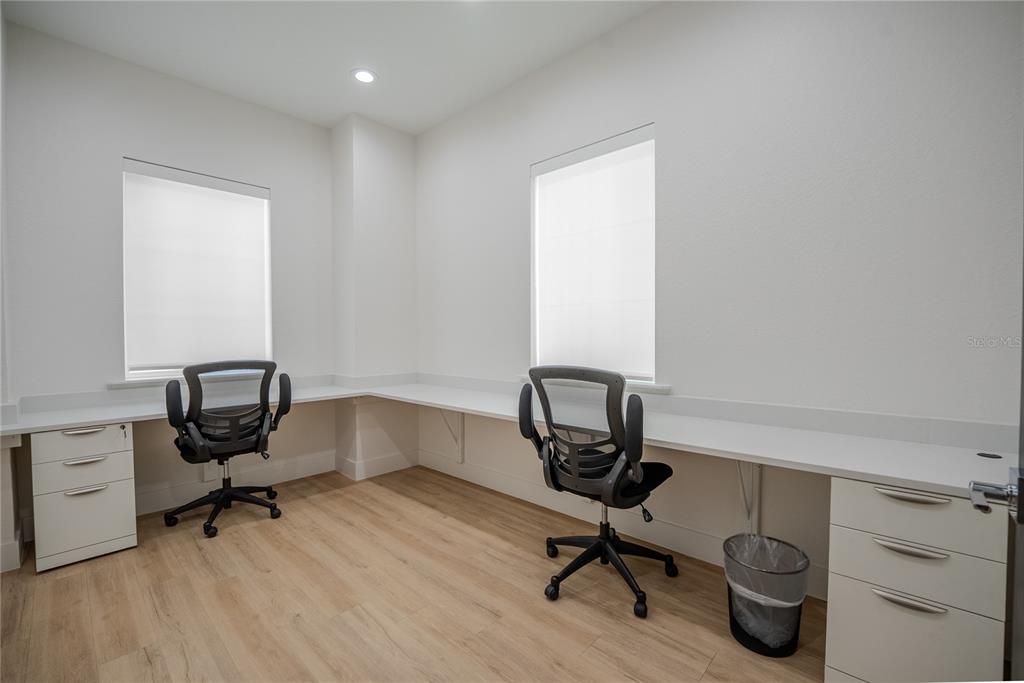A home office features a white L-shaped desk, two rolling chairs, and light wood flooring — 6601 SW 80TH AVENUE, OCALA, FL