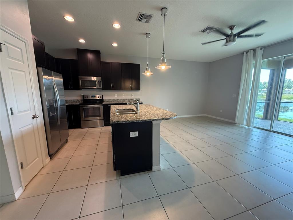 A kitchen features dark cabinets, granite countertops, a center island, and tile flooring — 6843 40TH LANE N, PINELLAS PARK, FL