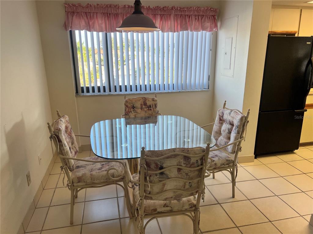 A dining area features a glass-topped table, four floral chairs, and a window with blinds — 1001 POINT OF ROCKS ROAD UNIT 408, SARASOTA, FL