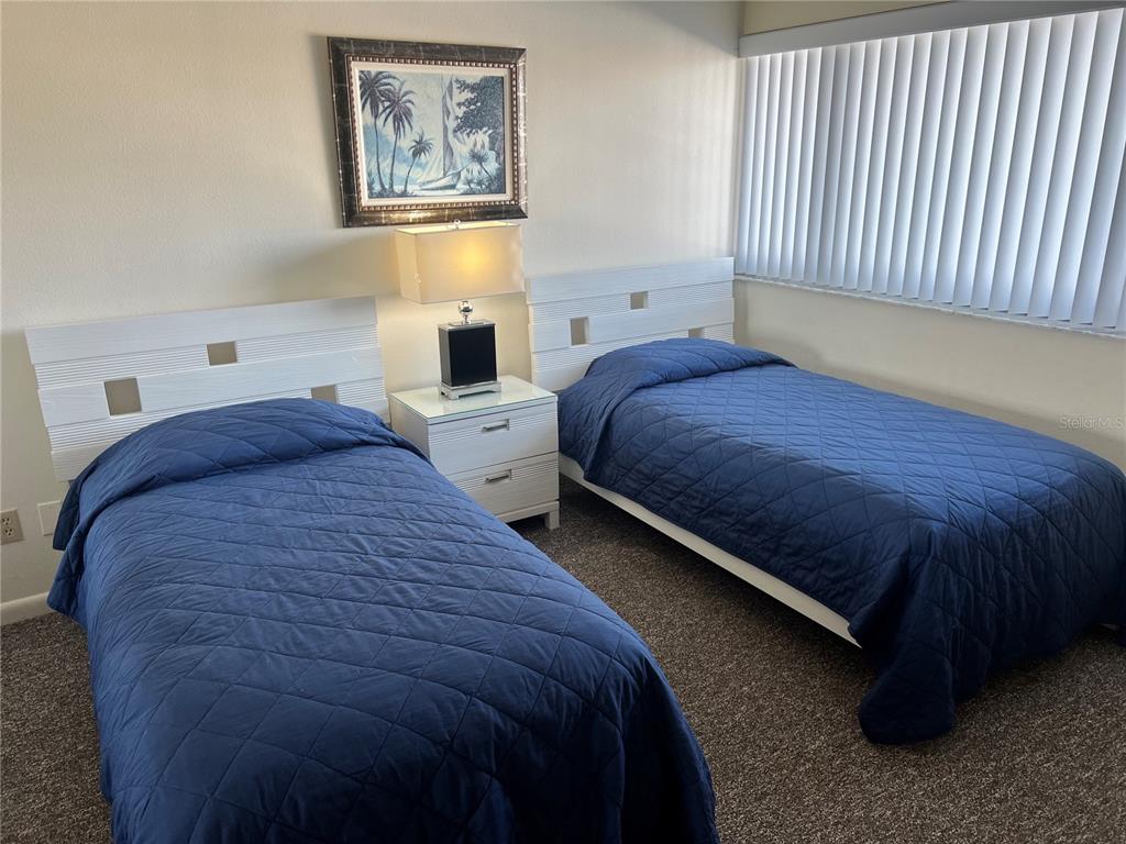 A bedroom features two twin beds with blue quilts, a nightstand, and a framed painting — 1001 POINT OF ROCKS ROAD UNIT 408, SARASOTA, FL