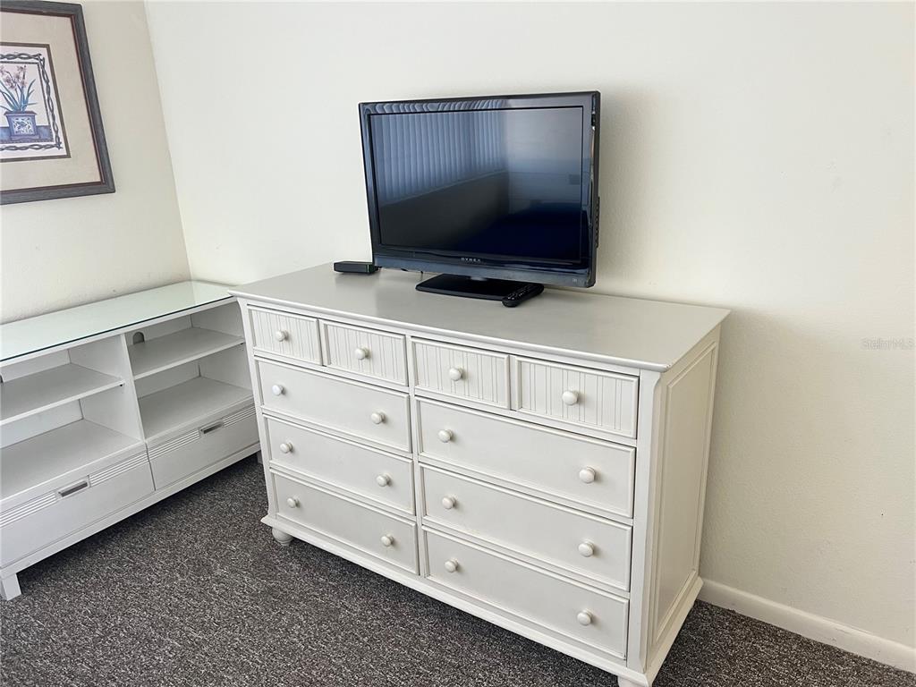 A white dresser with a television sits next to a white media console — 1001 POINT OF ROCKS ROAD UNIT 408, SARASOTA, FL