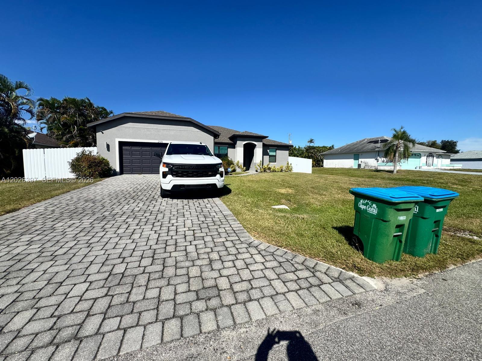 A white pickup truck is parked on a paved driveway in front of a house — 209 SE 26th Ter, Cape Coral FL 33904, CAPE CORAL, FL
