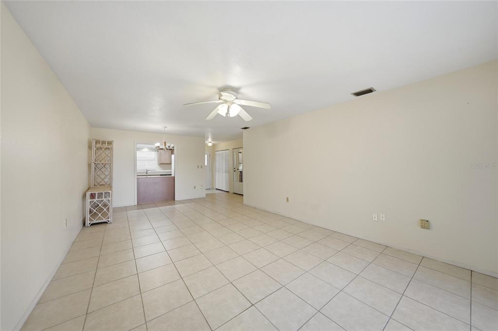 An open-concept living area features light-colored tile flooring, beige walls, and a ceiling fan — 1432 MEDITERRANEAN DRIVE UNIT 2B, PUNTA GORDA, FL
