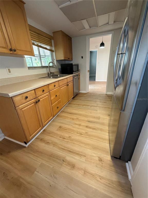 A kitchen features light wood cabinets, laminate countertops, stainless steel appliances, and wood-look flooring — 3024 BLOWN FEATHER LANE, MULBERRY, FL
