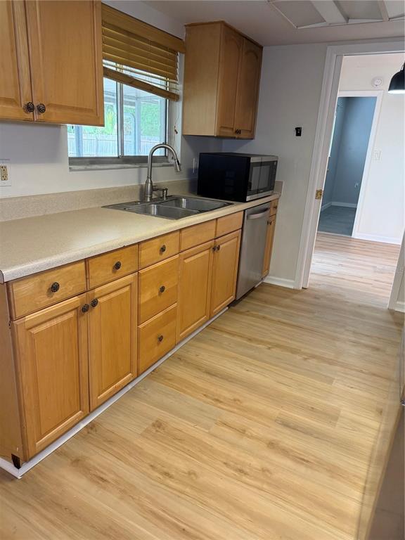 A kitchen features light wood cabinets, a stainless steel sink, and light-colored laminate flooring — 3024 BLOWN FEATHER LANE, MULBERRY, FL