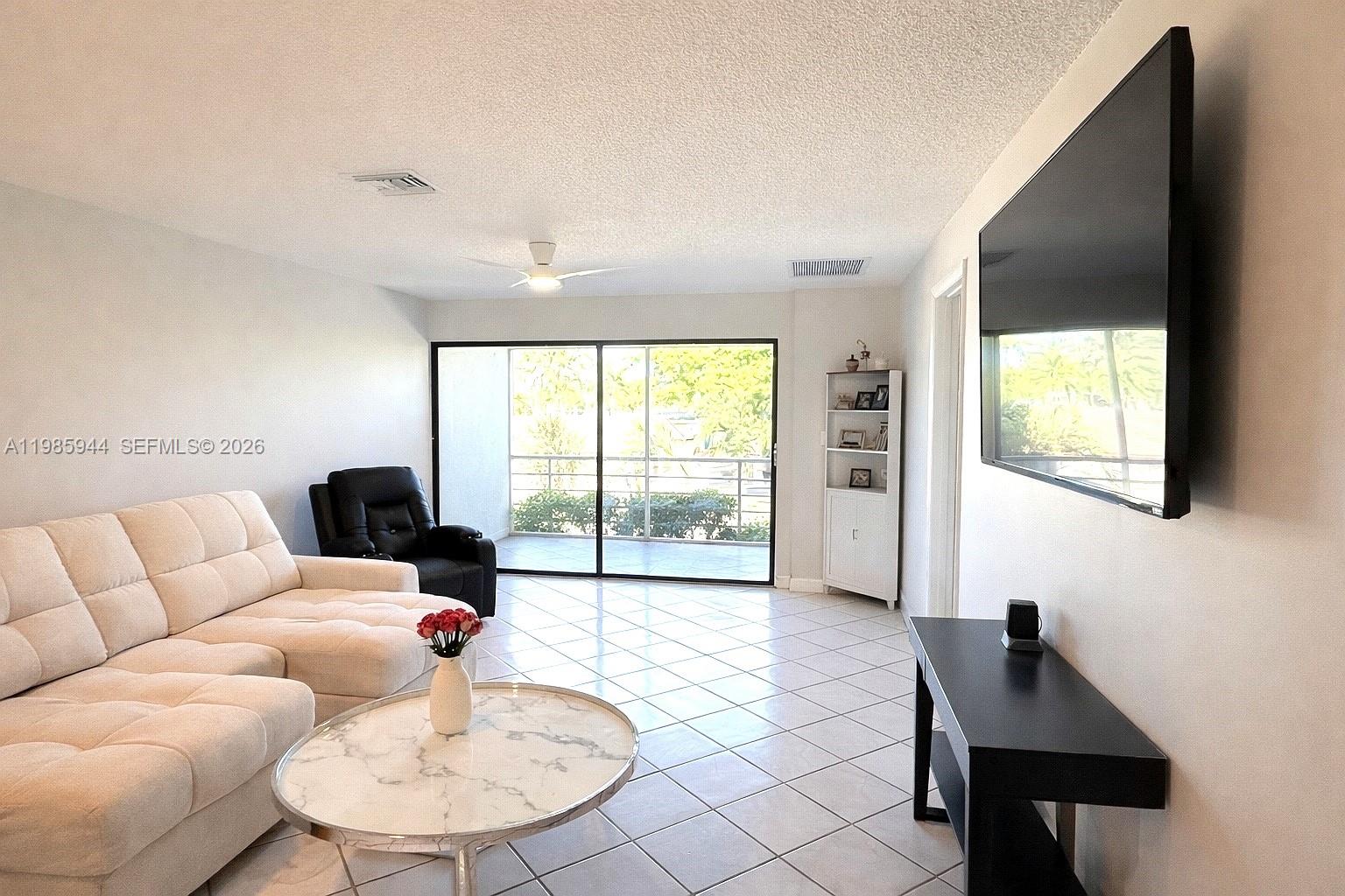 A living room features a white sectional sofa, marble coffee table, and wall-mounted television — 7830 NW 33rd St # 308, Davie FL 33024, DAVIE, FL