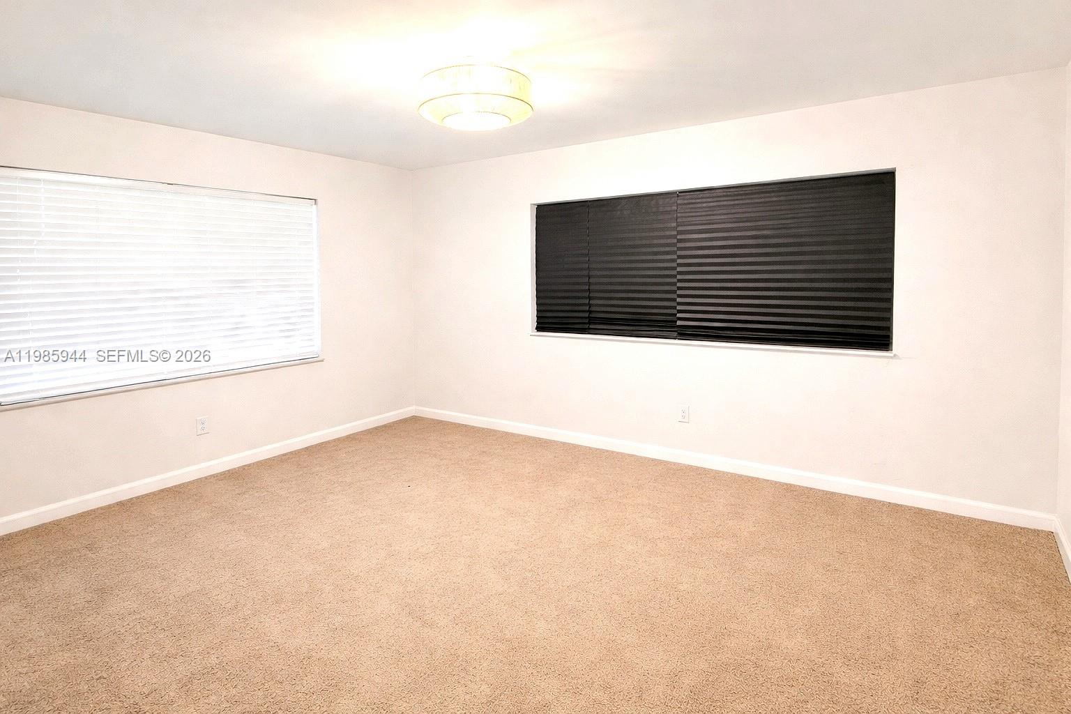 An empty bedroom features beige carpeting, white walls, and two windows with different blinds — 7830 NW 33rd St # 308, Davie FL 33024, DAVIE, FL