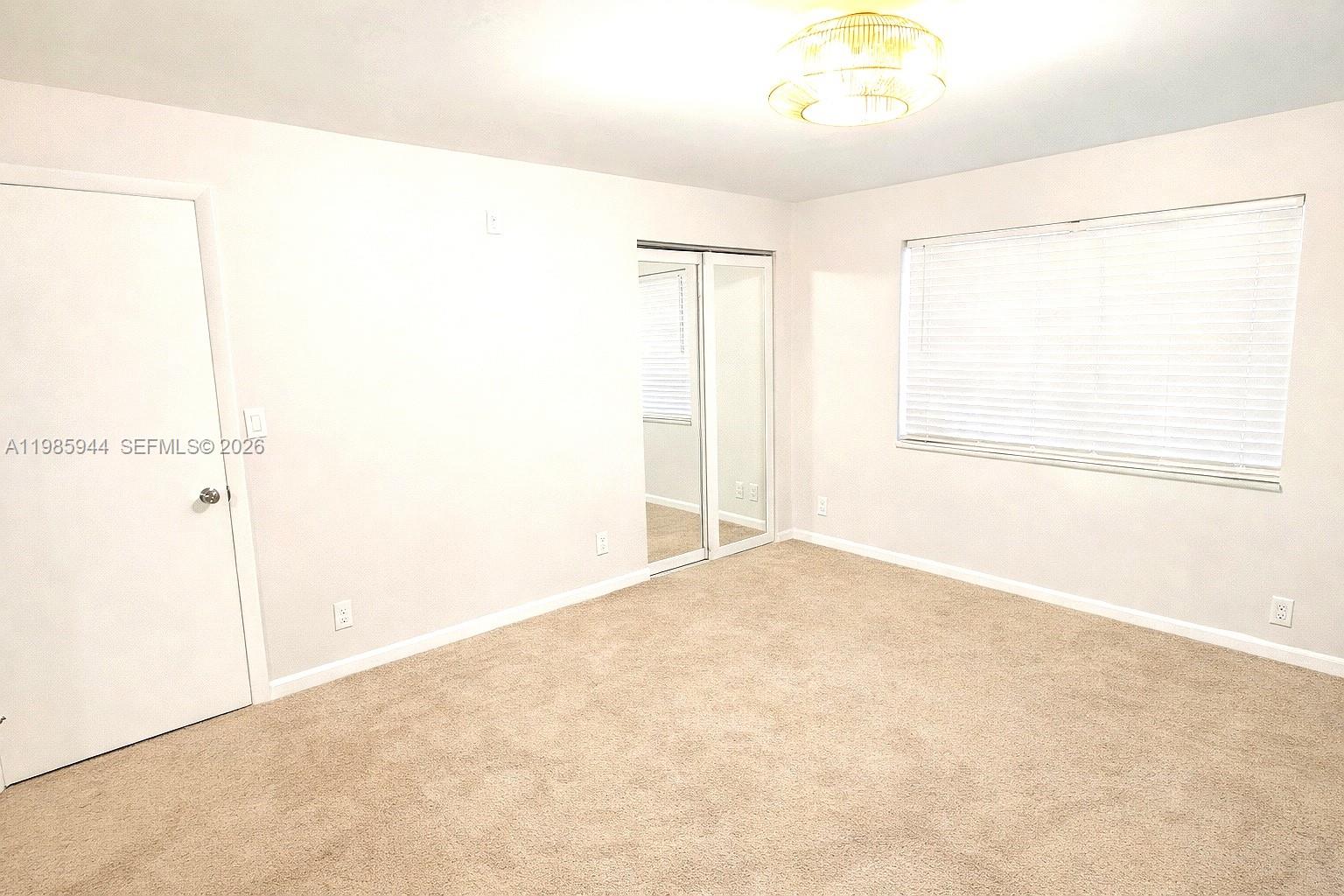 An empty bedroom features beige carpeting, white walls, a mirrored closet, and a window — 7830 NW 33rd St # 308, Davie FL 33024, DAVIE, FL