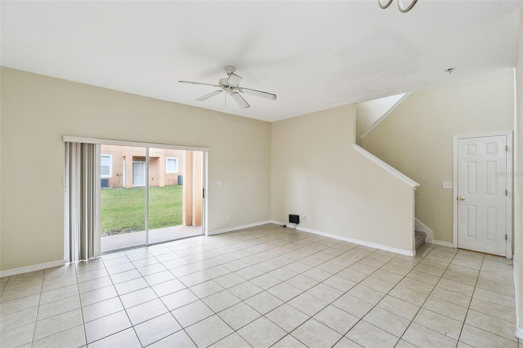 A bright living room features light tile flooring, a ceiling fan, and sliding glass doors — 2714 BUSHMAN DRIVE, KISSIMMEE, FL