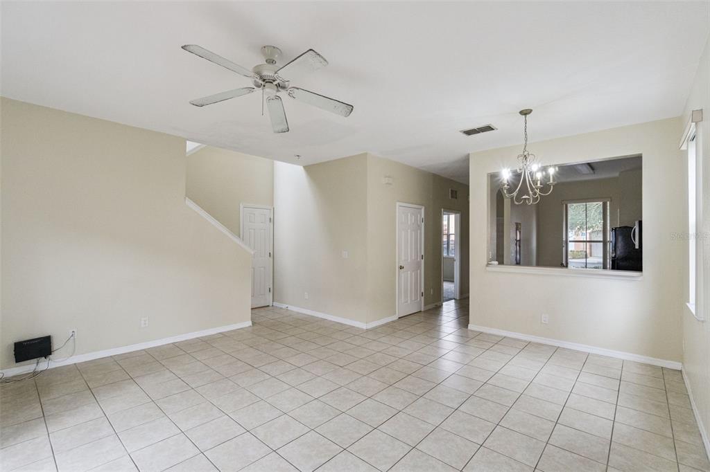 A bright, open-concept living and dining area features beige tile floors and a ceiling fan — 2714 BUSHMAN DRIVE, KISSIMMEE, FL