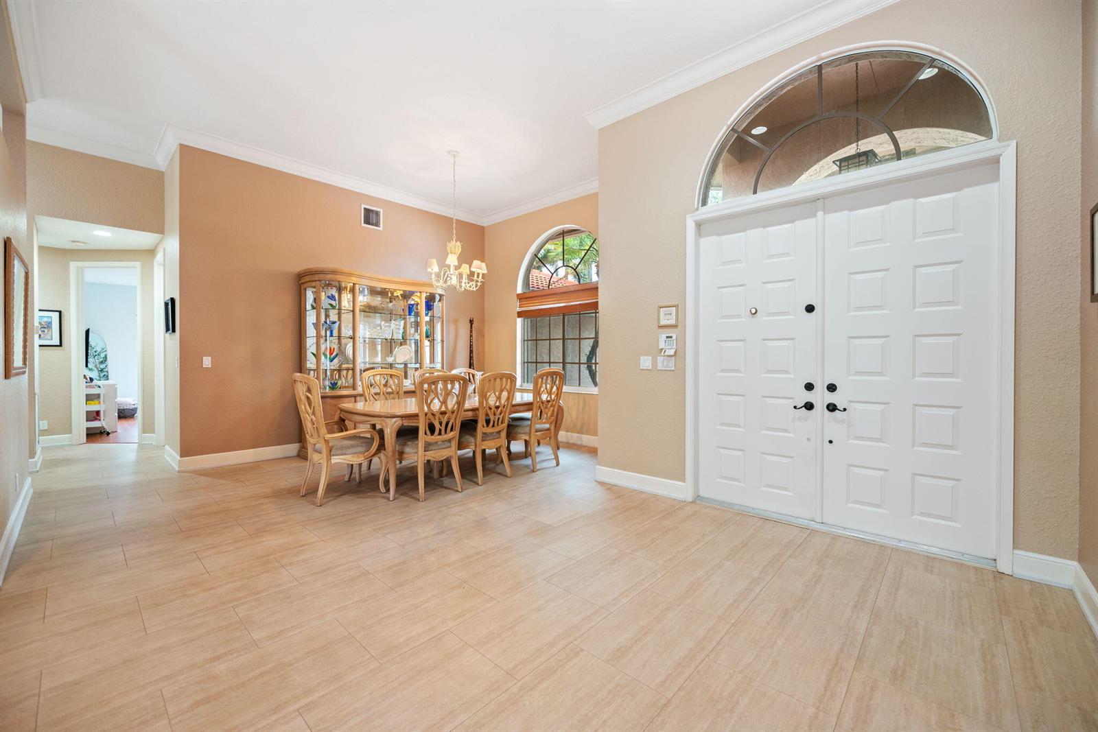 A dining area with a wooden table and hutch sits beside a white double-door entryway — 77 NW 108th Way, Plantation FL 33324, PLANTATION, FL