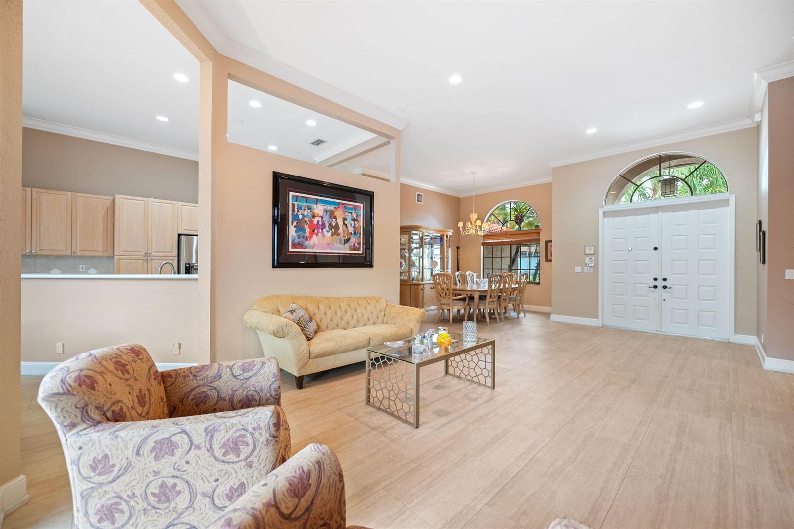 A living room with light tile floors, a tan sofa, patterned armchairs, and a dining area — 77 NW 108th Way, Plantation FL 33324, PLANTATION, FL
