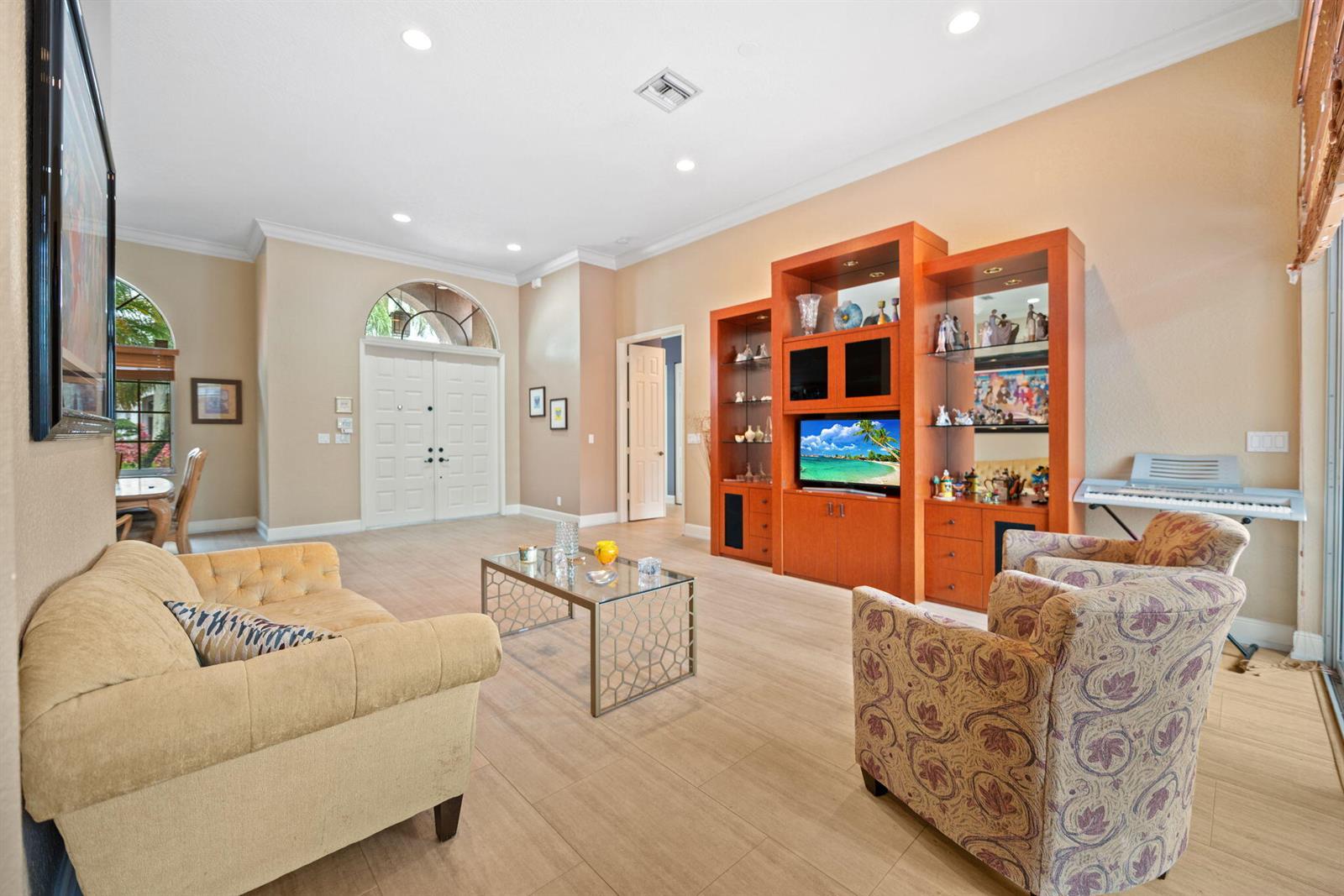 A living room with light tile floors, a wooden entertainment center, and patterned armchairs — 77 NW 108th Way, Plantation FL 33324, PLANTATION, FL