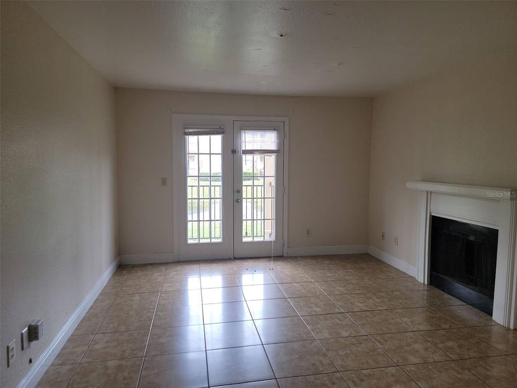 A living room with tile flooring, a fireplace, and French doors leading outside — 2550 N ALAFAYA TRAIL UNIT 2103, ORLANDO, FL