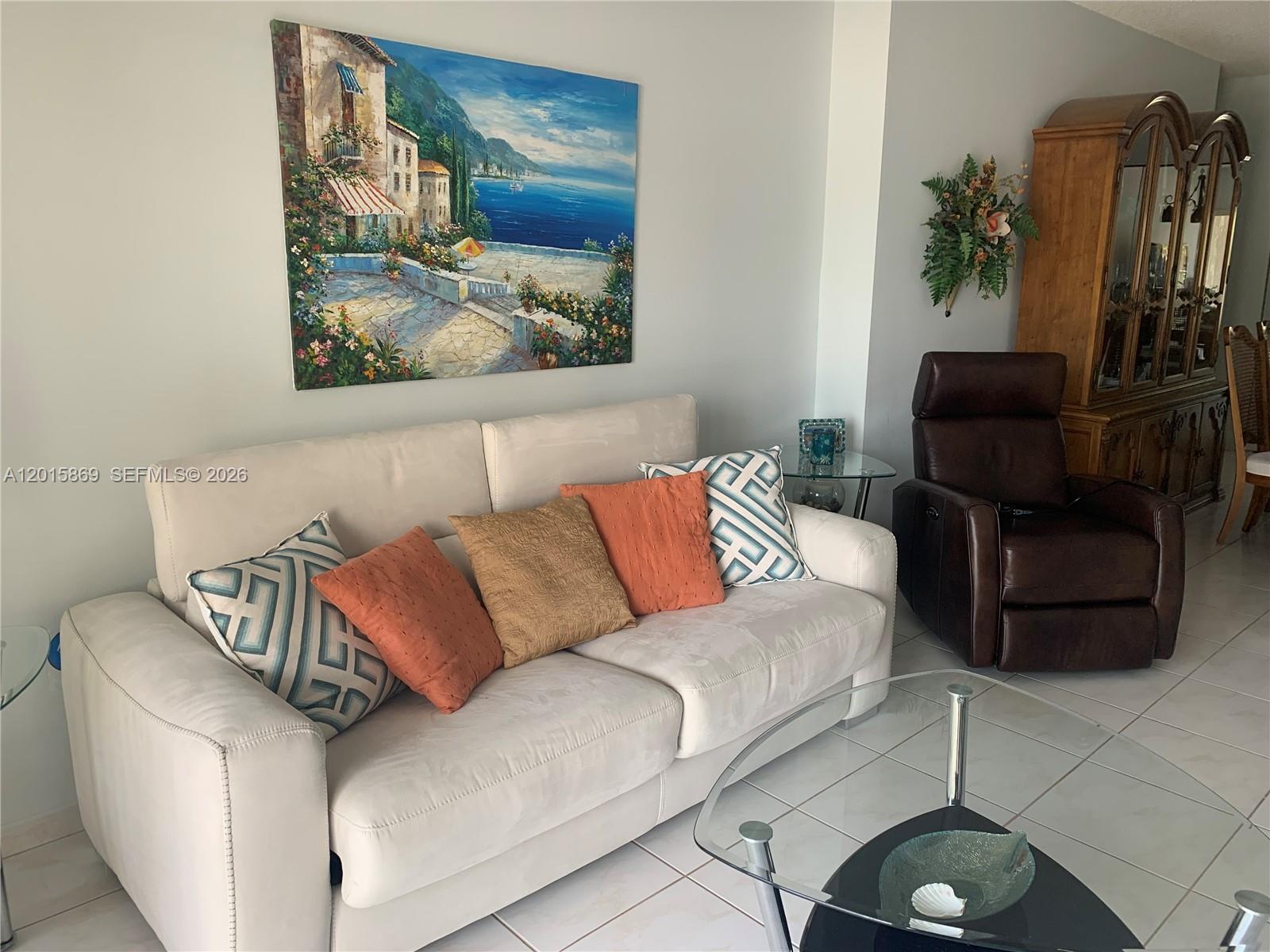 A living room features a white sofa with patterned pillows, a brown recliner, and artwork — 1985 S Ocean Dr, Hallandale Beach FL 33009, HALLANDALE BEACH, FL