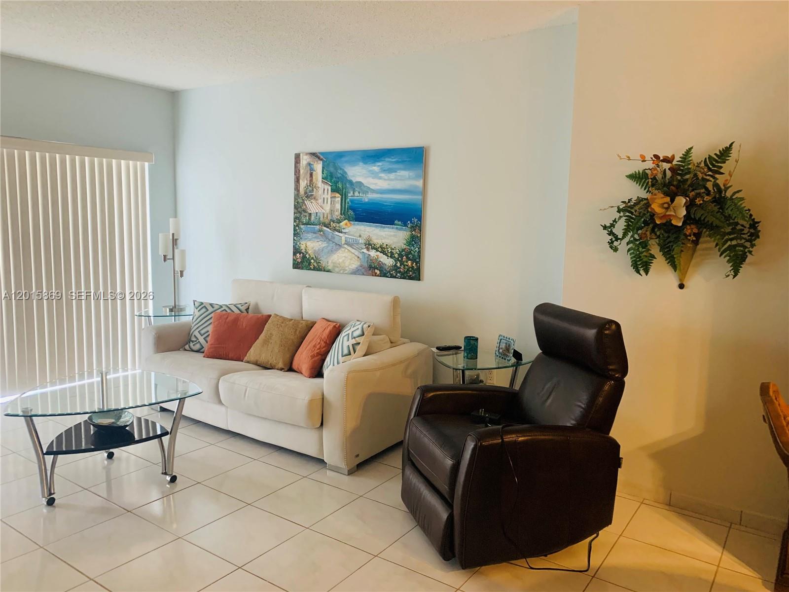 A living room features a white sofa, a dark leather recliner, and a glass coffee table — 1985 S Ocean Dr, Hallandale Beach FL 33009, HALLANDALE BEACH, FL