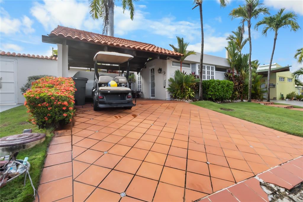 A tiled driveway leads to a covered carport with a golf cart parked in front — AD5 CALLE BALEARES, HUMACAO, PR