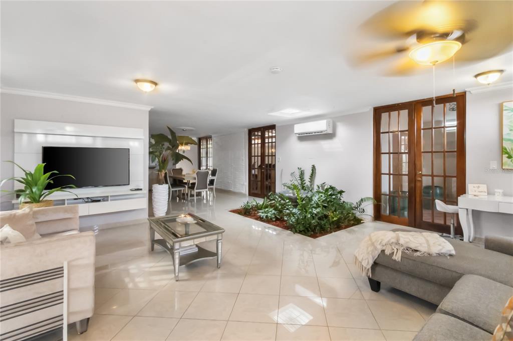 A living room with tile floors, a central indoor planter, and a wall-mounted television — AD5 CALLE BALEARES, HUMACAO, PR