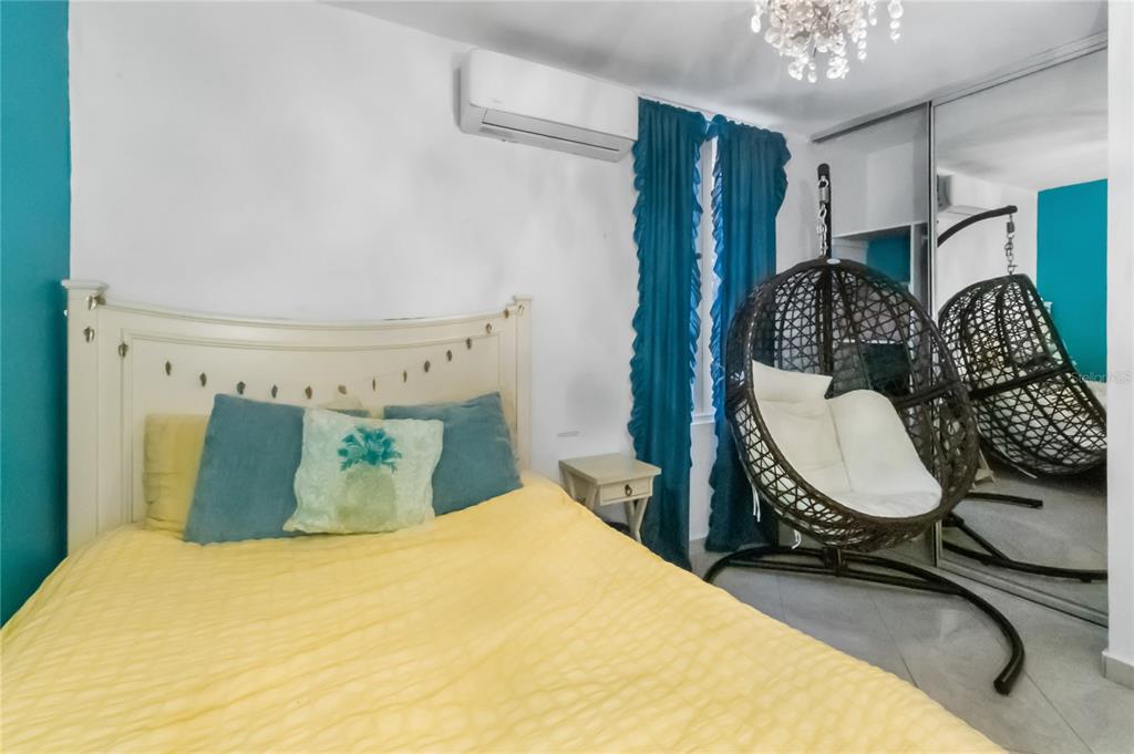 A bedroom features a yellow bed, a hanging egg chair, and blue curtains — AD5 CALLE BALEARES, HUMACAO, PR