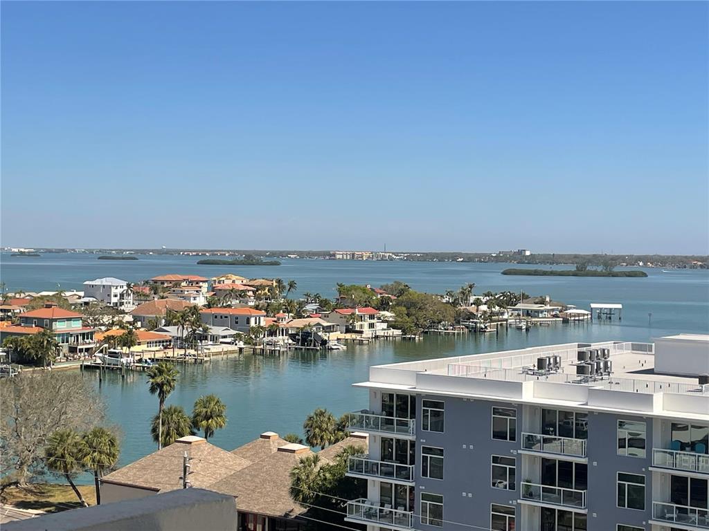 An elevated view of a coastal neighborhood with houses, a canal, and a modern apartment building — 400 ISLAND WAY UNIT 908, CLEARWATER BEACH, FL