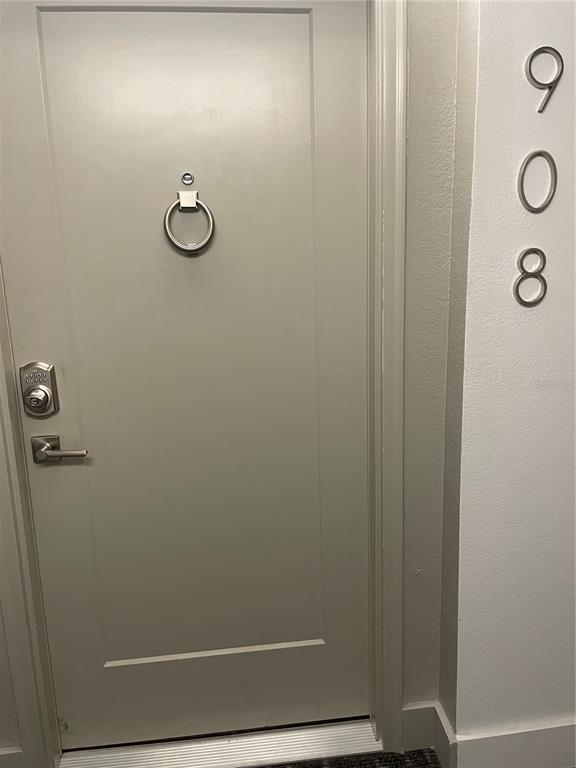 A light gray apartment door with a silver knocker, electronic lock, and unit number 908 — 400 ISLAND WAY UNIT 908, CLEARWATER BEACH, FL